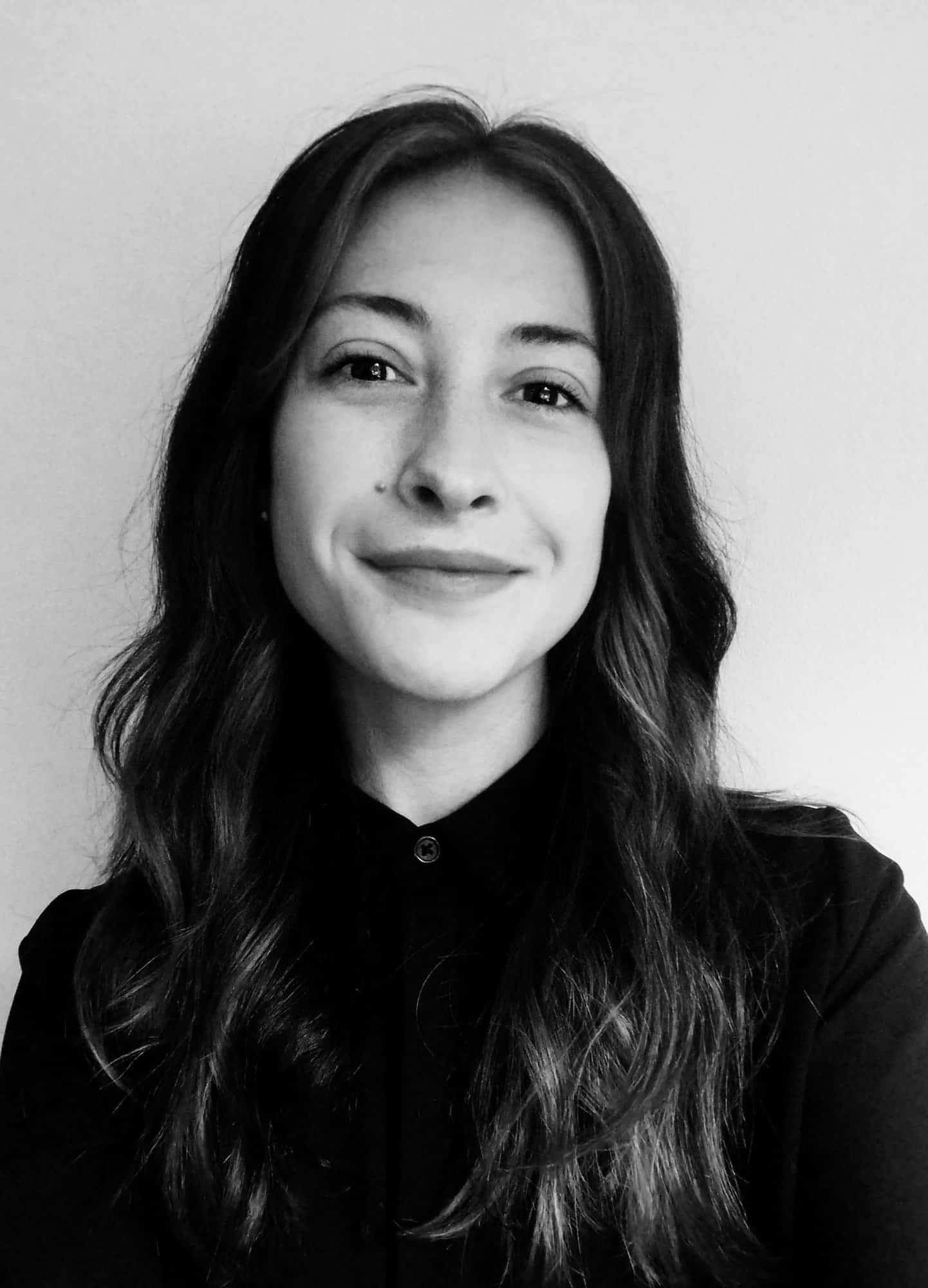 Black and white image of the head and shoulders of a young woman with long dark hair.